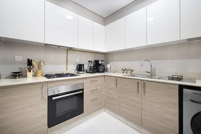 a kitchen with white cabinets and a stove top oven at Urban 1BR City view in The Bay Business Bay in Dubai
