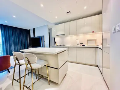 a kitchen with white cabinets and bar stools at Burj Khalifa View Modern 2BR CVG in Dubai