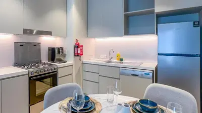 a kitchen with a table and chairs and a kitchen with a refrigerator at Peaceful 1BR in La Serine, Lush Garden Views - 1AB02 in Dubai