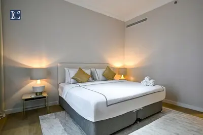a bedroom with a large white bed with two lamps at Luxury Escapes - Stylish 2-Bedroom Haven in La Cote, Port de La Mer in Dubai