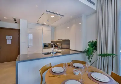 a dining room with a table and a kitchen at Burj Khalifa View - 2BR with Maids room in Canal Front 1, Al Wasl - Allsopp & Allsopp in Dubai