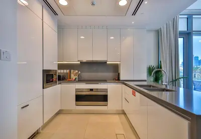 a kitchen with white cabinets and a black counter top at Burj Khalifa View - 2BR with Maids room in Canal Front 1, Al Wasl - Allsopp & Allsopp in Dubai