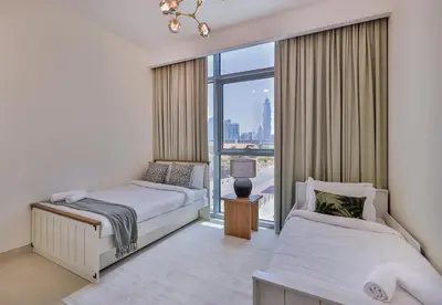a bedroom with two beds and a large window at Burj Khalifa View - 2BR with Maids room in Canal Front 1, Al Wasl - Allsopp & Allsopp in Dubai