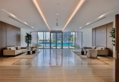 an empty lobby with couches and a pool at Burj Khalifa View - 2BR with Maids room in Canal Front 1, Al Wasl - Allsopp & Allsopp in Dubai