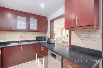 a kitchen with wooden cabinets and a microwave at LUX The Murjan Sea View Suite 2 in Dubai