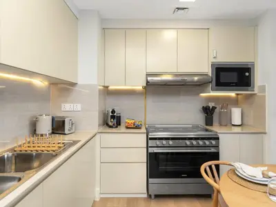 a kitchen with white cabinets and a black stove at The Town Square Suite Luxury 2BR Near Qudra Lake in Dubai