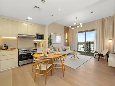 a kitchen and a living room with a table and chairs at The Town Square Suite Luxury 2BR Near Qudra Lake in Dubai