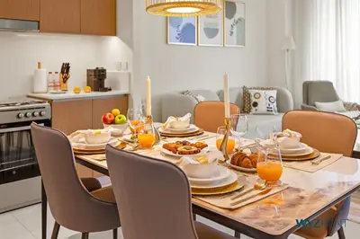 a dining room table with food and orange juice on it at Serene 1 BR in Surf 2-Creek Beach Access in Dubai