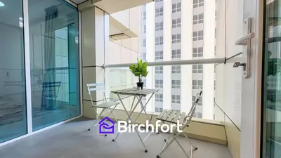 a balcony with a table and a chair on a building at Stylish Stay Steps from the Marina in Dubai
