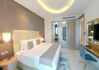 a bedroom with a large white bed and a television at Damac Paramount Tower in Dubai