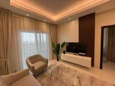 a living room with a television and a couch and a chair at Elegant One Bedroom in Sports City in Dubai