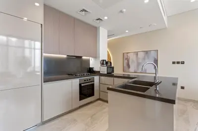 a kitchen with white cabinets and a sink at Sleek 1Bedroom with Burj Khalifa view in Peninsula in Dubai