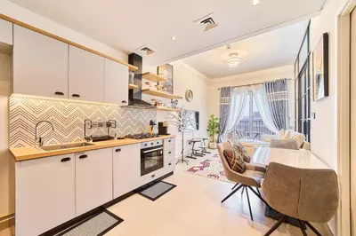 a kitchen with white cabinets and a table and chairs at Modern 1BR Retreat in Dubai Hills Prime Location in Dubai