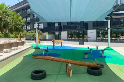 a resort with a playground with a slide and tires at Amazing 1BR with Pool in JVC in Dubai