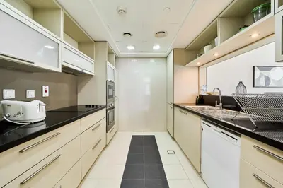 a kitchen with white cabinets and black counter tops at 2BR at Lofts West Near Dubai Mall and Burj Khalifa in Dubai