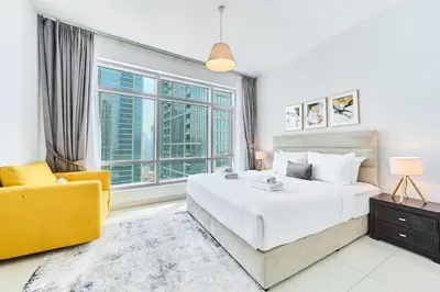 a bedroom with a large bed and a yellow chair at 2BR at Lofts West Near Dubai Mall and Burj Khalifa in Dubai