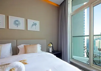 a bedroom with a bed and a large window at Modern Living DAMAC with Balcony & Waterfront Views in Dubai