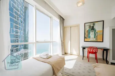 a bedroom with a bed and a desk and large windows at Private Beach - Tourist Spot - High Floor Residence in Dubai