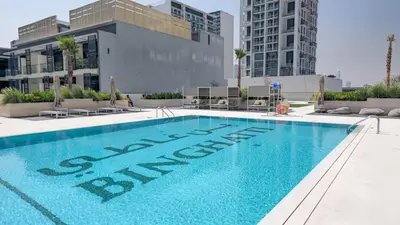 a swimming pool in front of a building at Brand New Luxurious - Modern 1BR - Pool - Gym in Dubai