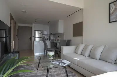 a white living room with a couch and a table at Brand New Luxurious - Modern 1BR - Pool - Gym in Dubai