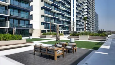 a patio with a table and chairs and a building at Brand New Luxurious - Modern 1BR - Pool - Gym in Dubai
