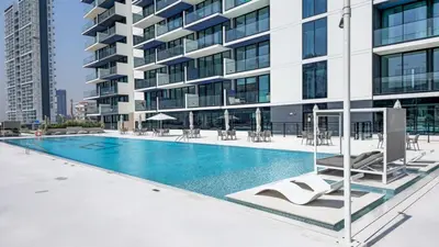 a swimming pool in front of a building at Brand New Luxurious - Modern 1BR - Pool - Gym in Dubai