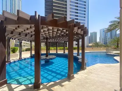 a large swimming pool with a wooden pergola at 1 Bedroom in Dubai Marina opp Dmcc metro station in Dubai