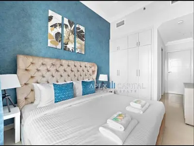 a bedroom with a large white bed with blue walls at 1 Bedroom in Dubai Marina opp Dmcc metro station in Dubai