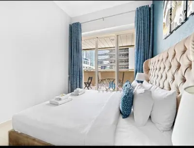 a bedroom with a large white bed and a window at 1 Bedroom in Dubai Marina opp Dmcc metro station in Dubai