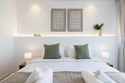 a bedroom with a white bed with green pillows at 3BR in Paramount with Panoramic Infinity Pool in Dubai