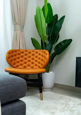 an orange chair in a living room with a plant at 2BR Apartment In Dubai in JVC near Circle mall in Dubai