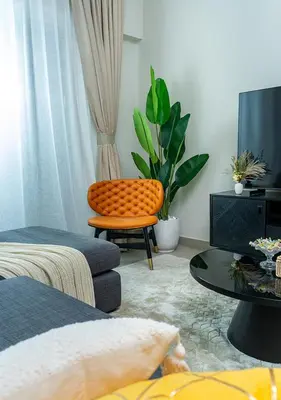 a living room with an orange chair and a tv at 2BR Apartment In Dubai in JVC near Circle mall in Dubai