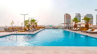 a large swimming pool with chairs and a city at High-Rise Studio Near the Golf Club and Mall with a Community View,Damac Hills Artesia Tower D, Dubailand by Deluxe Holiday Homes in Dubai
