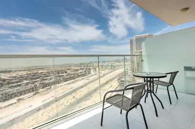 a balcony with a table and chairs and a view of the beach at High-Rise Studio Near the Golf Club and Mall with a Community View,Damac Hills Artesia Tower D, Dubailand by Deluxe Holiday Homes in Dubai