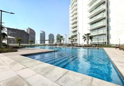 a swimming pool in a city with a tall building at High-Rise Studio Near the Golf Club and Mall with a Community View,Damac Hills Artesia Tower D, Dubailand by Deluxe Holiday Homes in Dubai