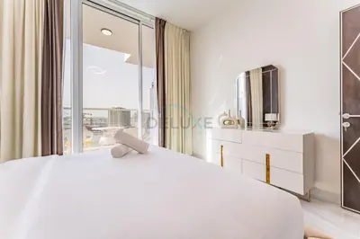 a bedroom with a white bed and a large window at City Views 2BR and Assistant Room with Mini Private Pool in Balcony, Gemz by Danube, Al Furjan by Deluxe Holiday Homes in Dubai