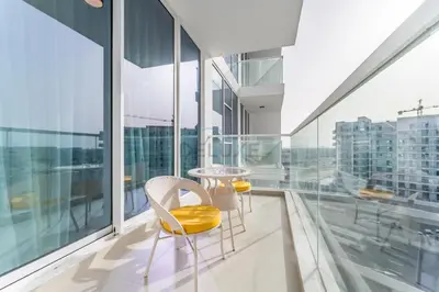 a balcony with yellow chairs and a table on a building at City Views 2BR and Assistant Room with Mini Private Pool in Balcony, Gemz by Danube, Al Furjan by Deluxe Holiday Homes in Dubai