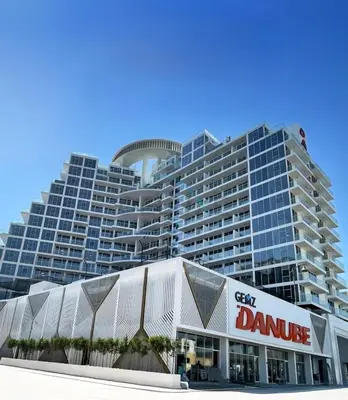 a large building with a dmg sign in front of it at City Views 2BR and Assistant Room with Mini Private Pool in Balcony, Gemz by Danube, Al Furjan by Deluxe Holiday Homes in Dubai