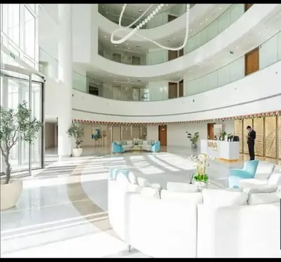 a lobby with white chairs and a man standing in a building at Fleur Star Apartments in Dubai