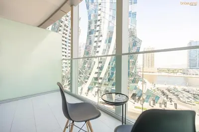 a chair and a table in a room with a large window at Bnbeyond's Artsy Canal-View Studio in the Heart of BBay in Dubai