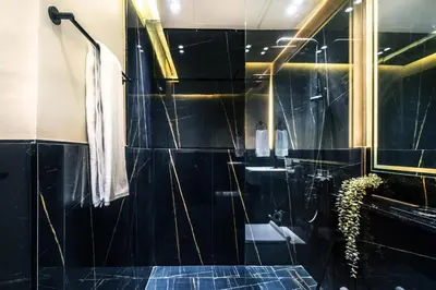 a bathroom with a shower with a black tiled wall at The Smart Concierge - Binghatti Canal in Dubai