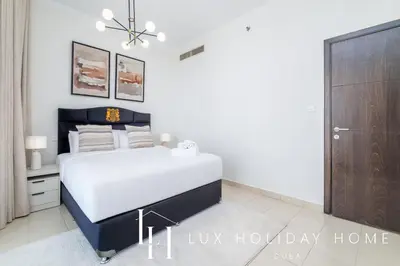 a white bedroom with a bed and a chandelier at LUX The Dubai Marina View Suite 2 in Dubai
