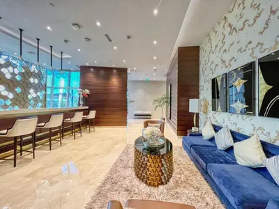 a living room with a blue couch and a bar at The Smart Concierge - Damac Heights in Dubai