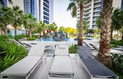 a resort with palm trees and a fountain at Moderne 1BR apartment overlooking city in Dubai