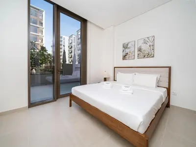 a white bedroom with a large bed and large windows at Modern 1-Bed Escape with Large Terrace, Creek Beach Dubai in Dubai