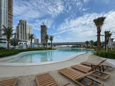 a swimming pool with two lounge chairs and a bridge at Modern 1-Bed Escape with Large Terrace, Creek Beach Dubai in Dubai