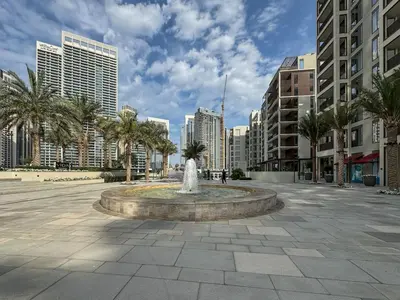 a fountain in a square in a city with tall buildings at Modern 1-Bed Escape with Large Terrace, Creek Beach Dubai in Dubai