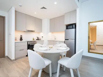 a kitchen with a white table and chairs in a room at Modern 1-Bed Escape with Large Terrace, Creek Beach Dubai in Dubai