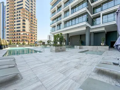 a patio with chairs and a pool in front of a building at Stylish JVC 1 Bed with Wraparound Balcony in Dubai