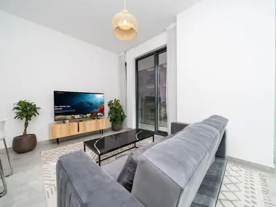 a living room with a couch and a flat screen tv at Stylish JVC 1 Bed with Wraparound Balcony in Dubai